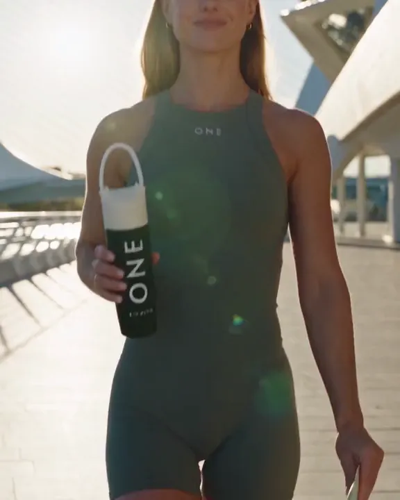 A runner with a water bottle on a sunlit promenade