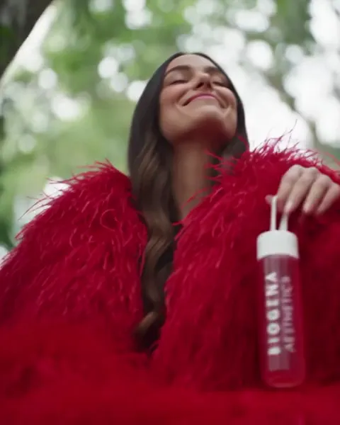 A woman in a red feathered coat in the rainforest